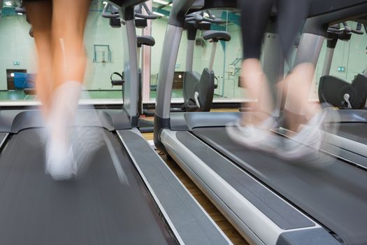 Two people running on treadmills in the gym