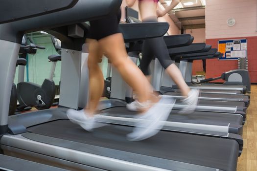 Two people running on treadmills in the gym side by side