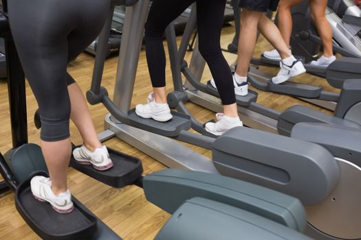 Four people stepping on step machine in gym 