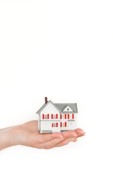 Hand holding a miniature house on a white background