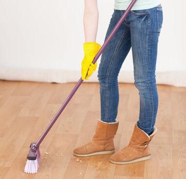 Attractive red-haired woman sweeping the floor at home