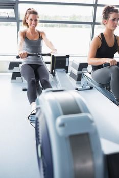Two people training on row machines in gym