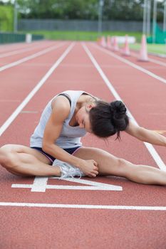 Woman stretching her leg on a track 
