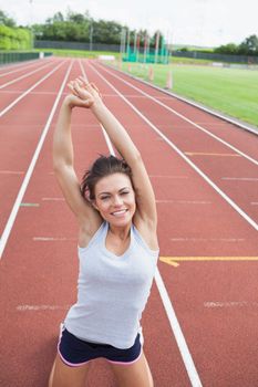 Happy woman stretching her arms on a track