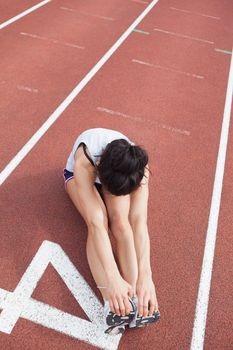 Female runner stretching legs on running track