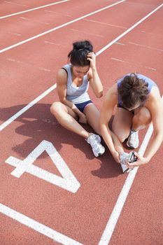Woman caring about runner with sports injury on running track