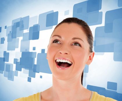 Woman looking up against blue background and smiling