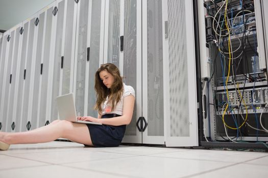 Woman sitting on floor working on laptop in data center