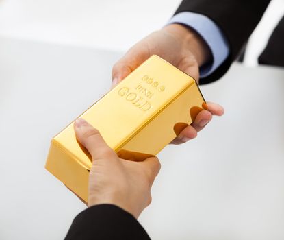 Close-up on hand of business people exchanging golden bar