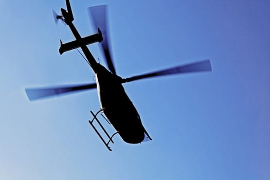 Generic silhouette of an helicopter caught  in flight against a clear blue sky. Actual location was Kashmir India but could have been taken anywhere on the globe