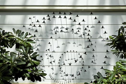 Interior feature over a pond, backdrop of metal cut out birds in stages of flight with plants in the foreground. A generic shot taken in Goa, India