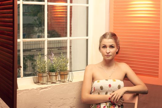 Girl sitting near an open window of the house