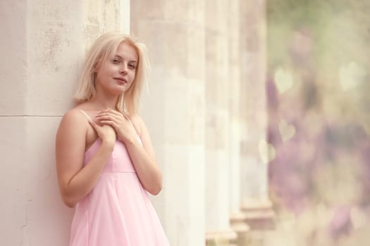 young woman in summer dress  against old stone wall, outdoor shot