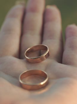 Two wedding rings lie on the palm