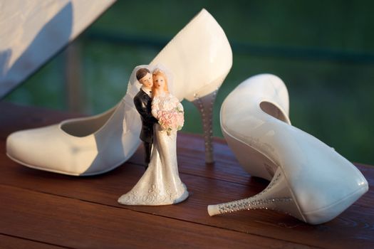 bridal shoes near the bride and groom figurines