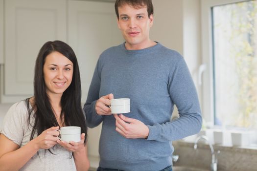 Two people standing in the kitchen and drinking coffee