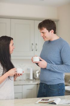 Two people standing in the kitchen and drinking coffee while talking