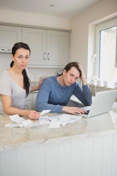 Two people working on finances while using the laptop in the kitchen