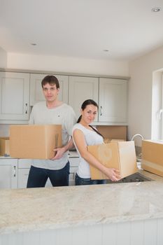 Two young people standing in the kitchen while holding boxes for a relocation