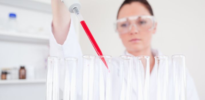 Beautiful red-haired scientist filling up a test tube in a lab