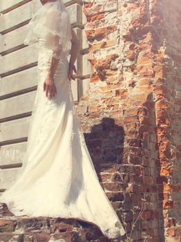 The bride with a long train on the background of the old wall