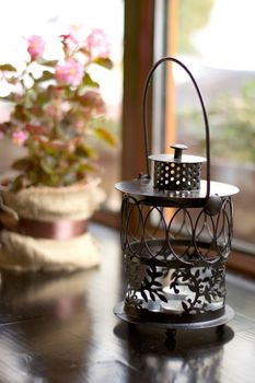 Black candlestick on a wooden windowsill near a flower in a pot