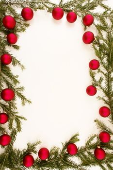 Border of red christmas garland with baubles and ribbons on white.