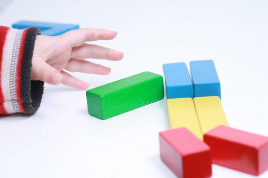 child hands play isolated toy with wooden blocks