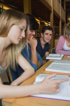 Students in the college library in a study group with one looking up and smiling