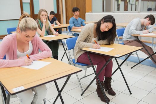 People sitting at the classroom while writing
