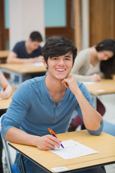 Student looking up and smiling during exam in exam hall in college