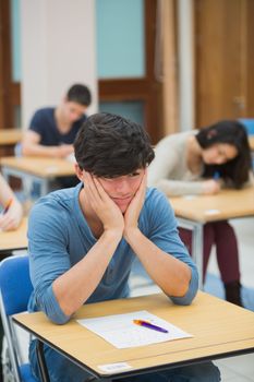 Student looking helpless taking an exam in exam hall of college