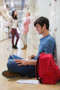 Man sitting on the floor at the hallway holding a laptop