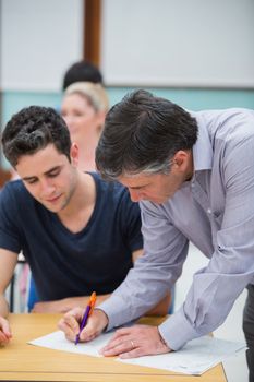 Teacher making note on students work in classroom