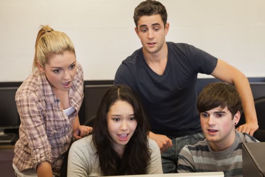 Students sitting at the computer looking shocked in college