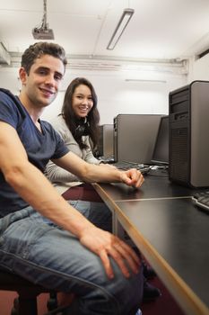 Man and woman sitting at desk at the computer room 