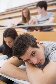 Student leaning at the desk at the lecture hall having a rest