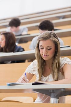 Woman sitting while writing notes at the lecture hall 