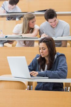 Student using laptop to take notes in lecture hall