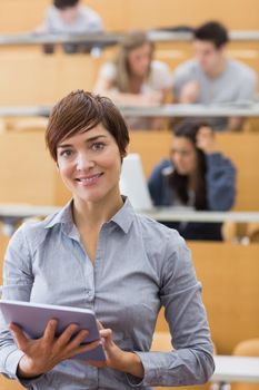 Woman standing holding a tablet computer smiling at the lecture hall 