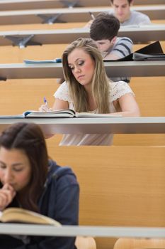 Students sitting at the lecture hall while writing and taking notes