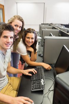 Students sitting at the computer room while smiling in college