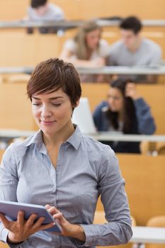 Teacher standing holding a tablet computer at the lecture hall 