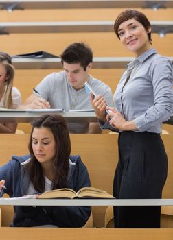 Students working while teacher smiling at the lecture hall 