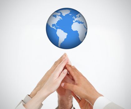People joining and reaching hands up to a globe 