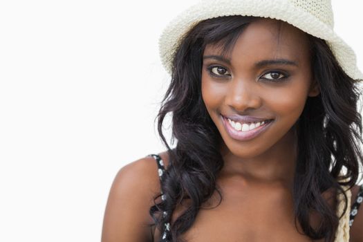 Woman wearing summer hat while smiling against white background