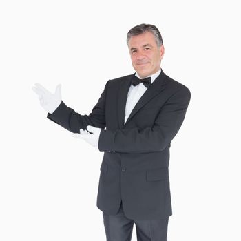 Smiling waiter in suit showing us something