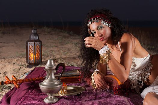Attractive brunette drinking Moroccan tea in a desert setting