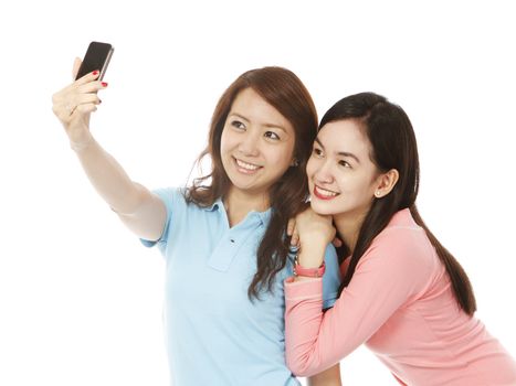 Two young women taking their own photos using a phone camera (on white background)