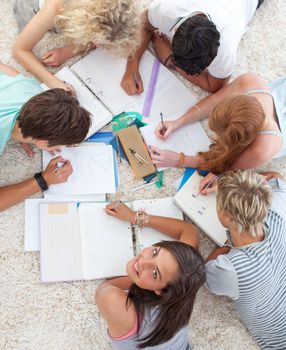 High angle of teenagers lying on the ground studying together